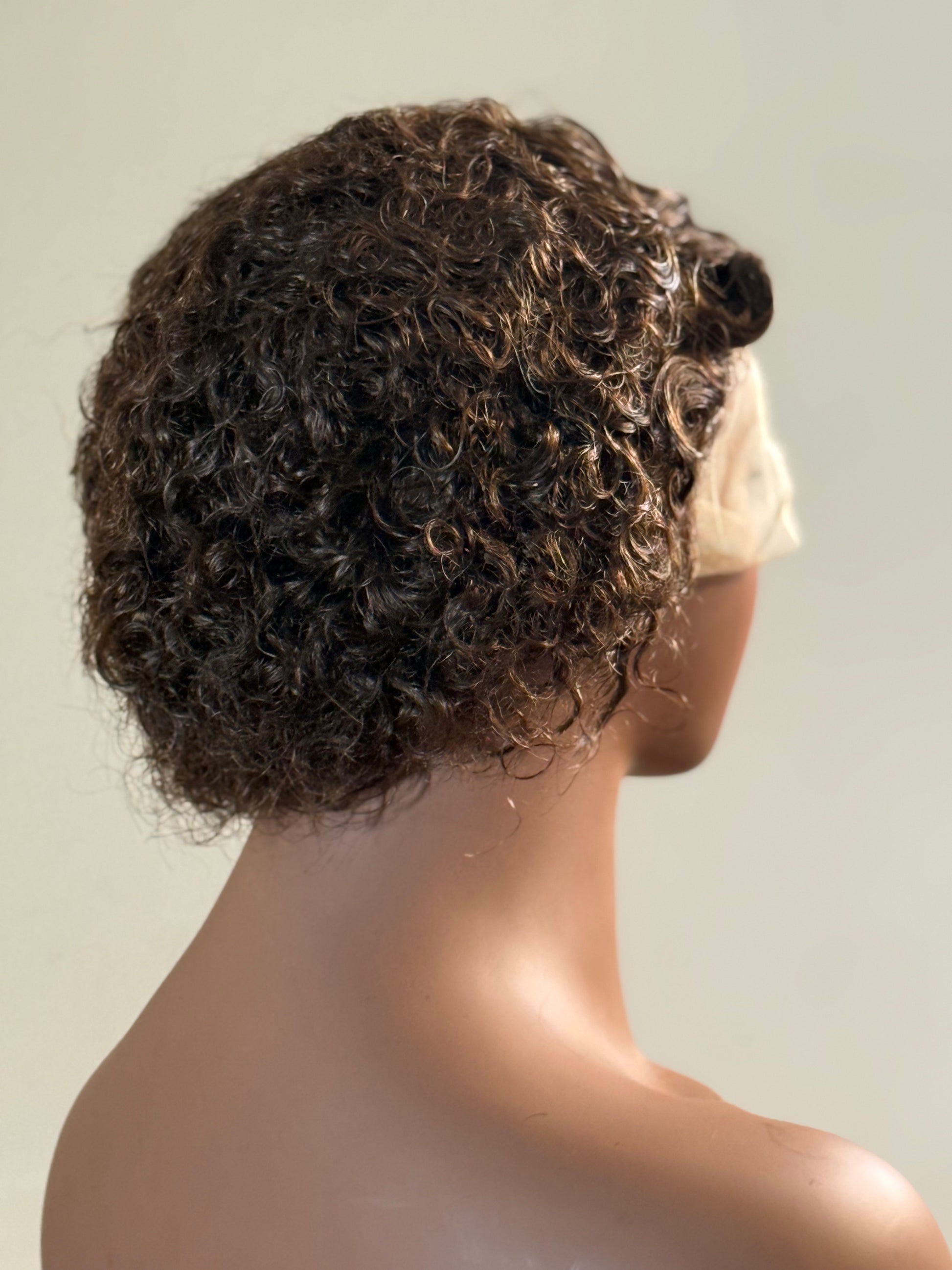 Mannequin head with a curly wig on a plain background